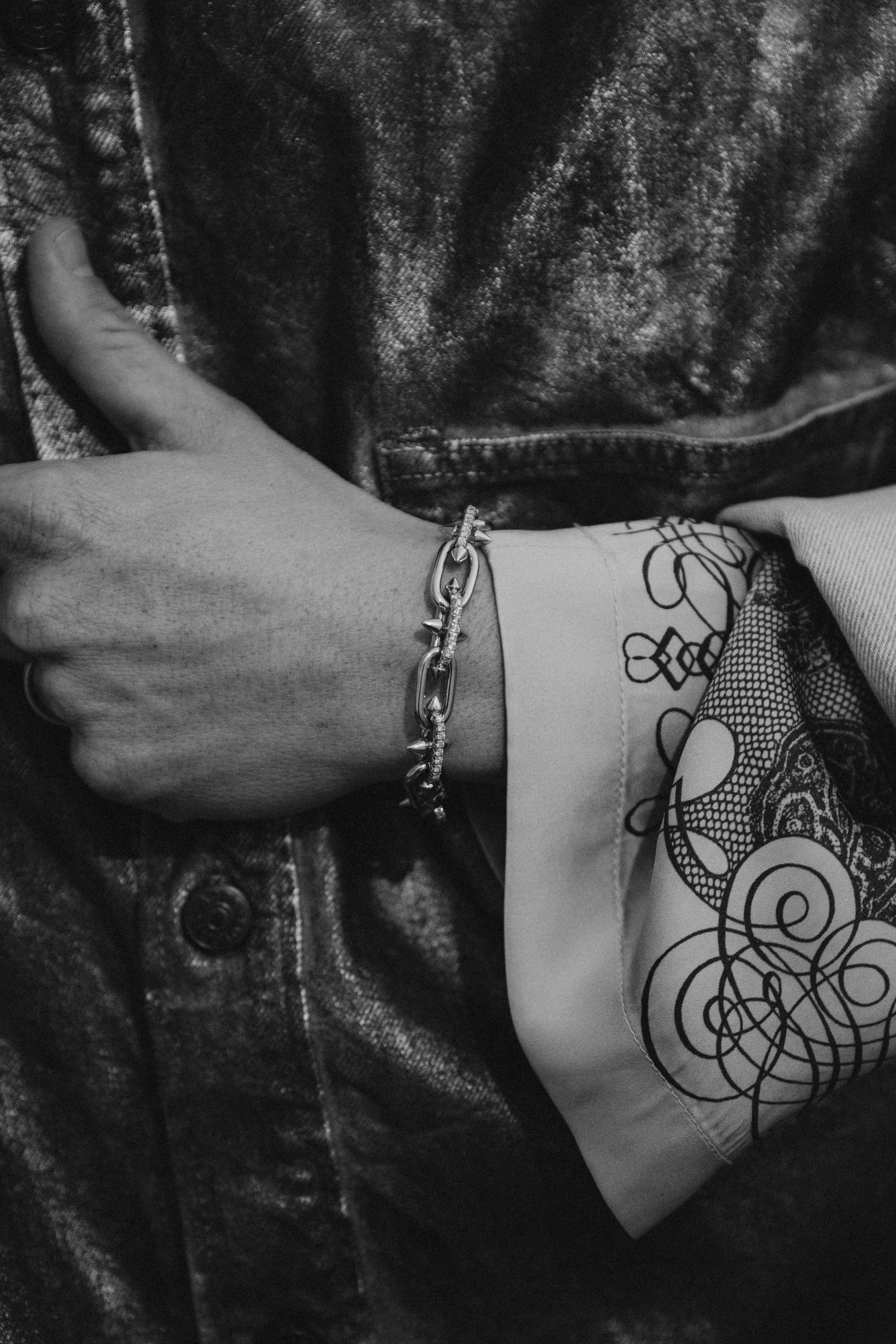 Detail in Schwarzweiß: Hand mit Armband und Tätowierung